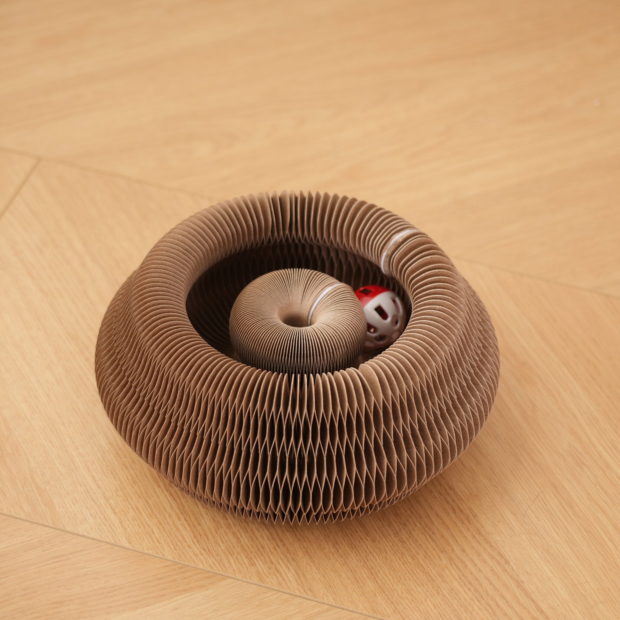Magic Coil Katzenspielzeug aus Kraftpapier zu einem Nest geformt mit rotem Glöckchenball